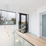 the curved glass balustrade and designer pendant lights are a beautiful introduction to the main living area of the house, the lift enhances accessibility and the glass step adds light and a feeling of space